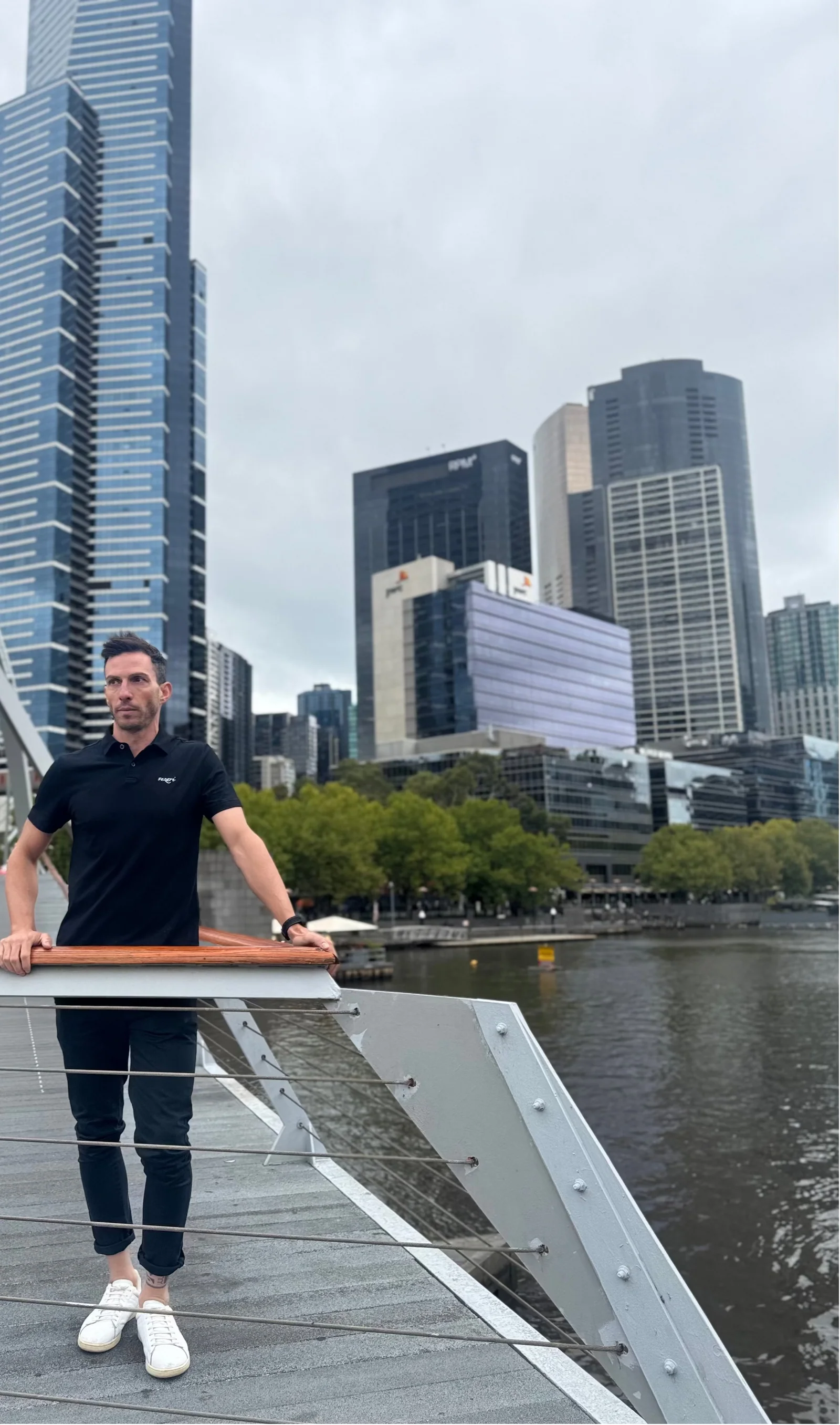 Man in the black Casual Fit Polo leaning on a railing by the Yarra River